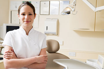 a smiling dental assistant standing in a dental exam room