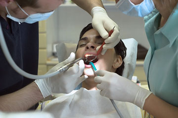a dentist and his assistant using a dentist drill on a patient